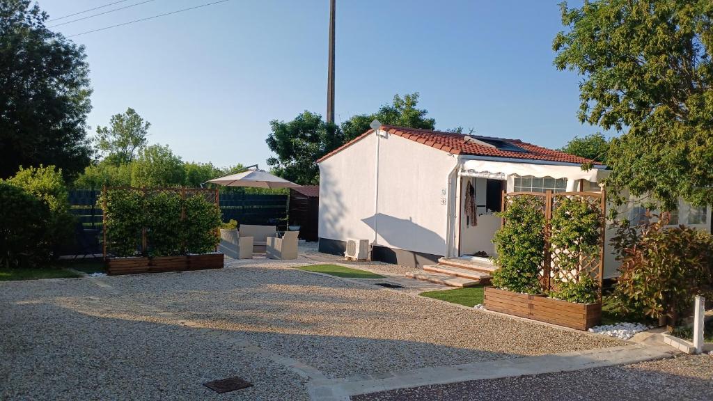 une petite maison blanche avec une cour arborée dans l'établissement 2 stars - Dans Résidence de Loisirs, à Saint-Pierre-dʼOléron
