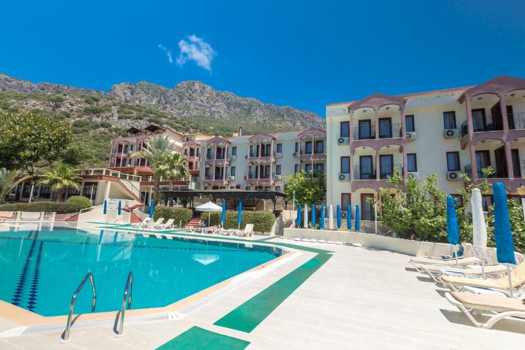 a swimming pool at a resort with mountains in the background at Hotel Club Phellos in Kaş