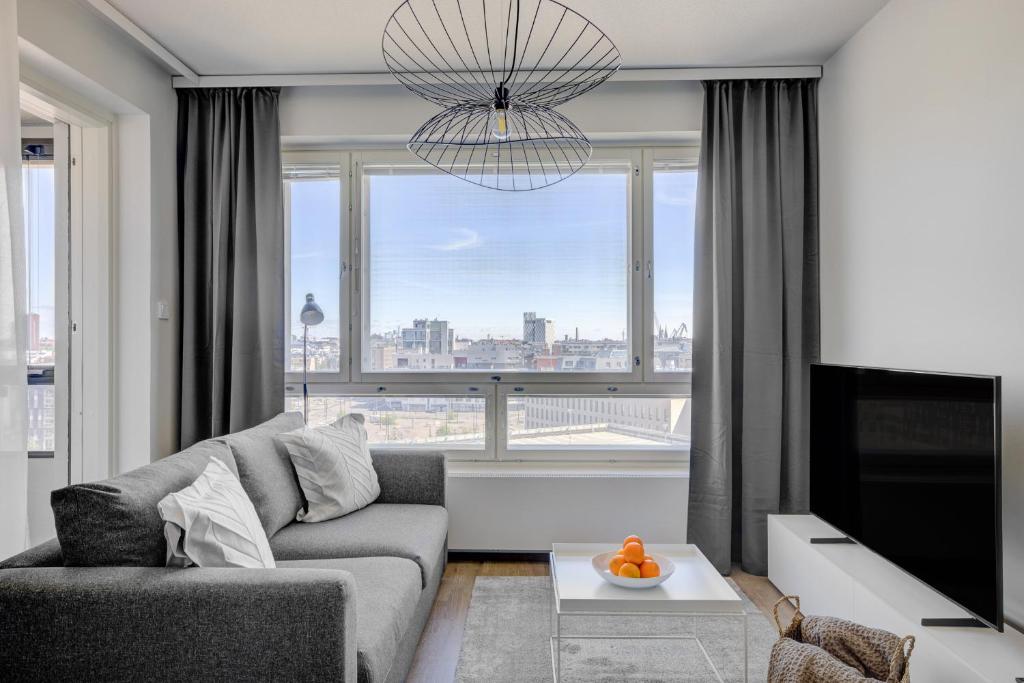 a living room with a couch and a large window at Modern and Stylish 1BR with Balcony and City View in Helsinki