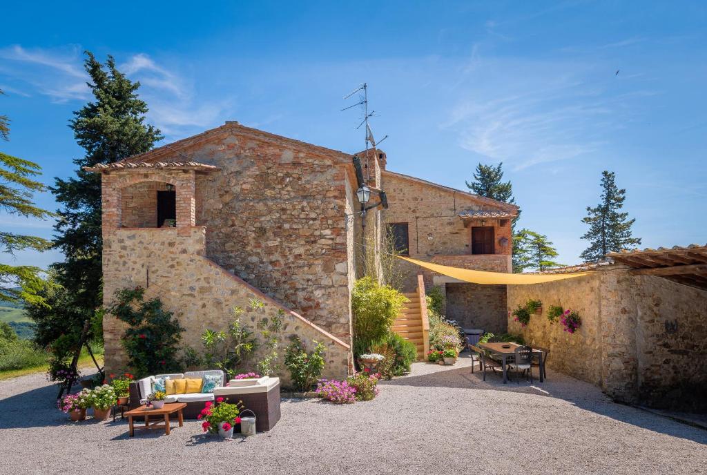 カステルヌオーヴォ・ディ・ヴァル・ディ・チェーチナにあるPodere le Roteの石造りの建物で、その前にテーブルと椅子があります