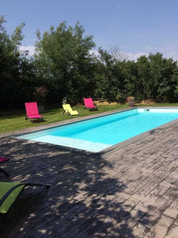 - une piscine avec 2 chaises roses dans la cour dans l'établissement Gîte Le Ménicou, à Montaut