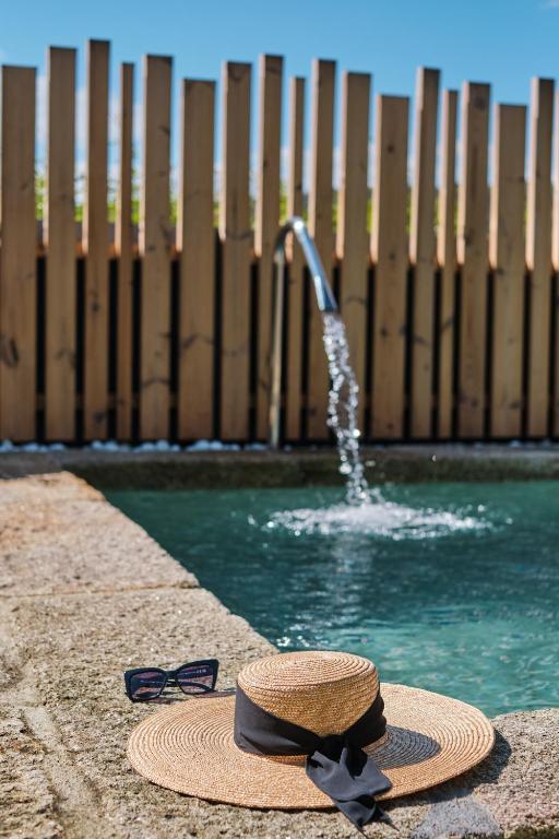 einen Hut und eine Sonnenbrille neben einem Pool in der Unterkunft Hotel Gaio 7 in Santiago de Compostela