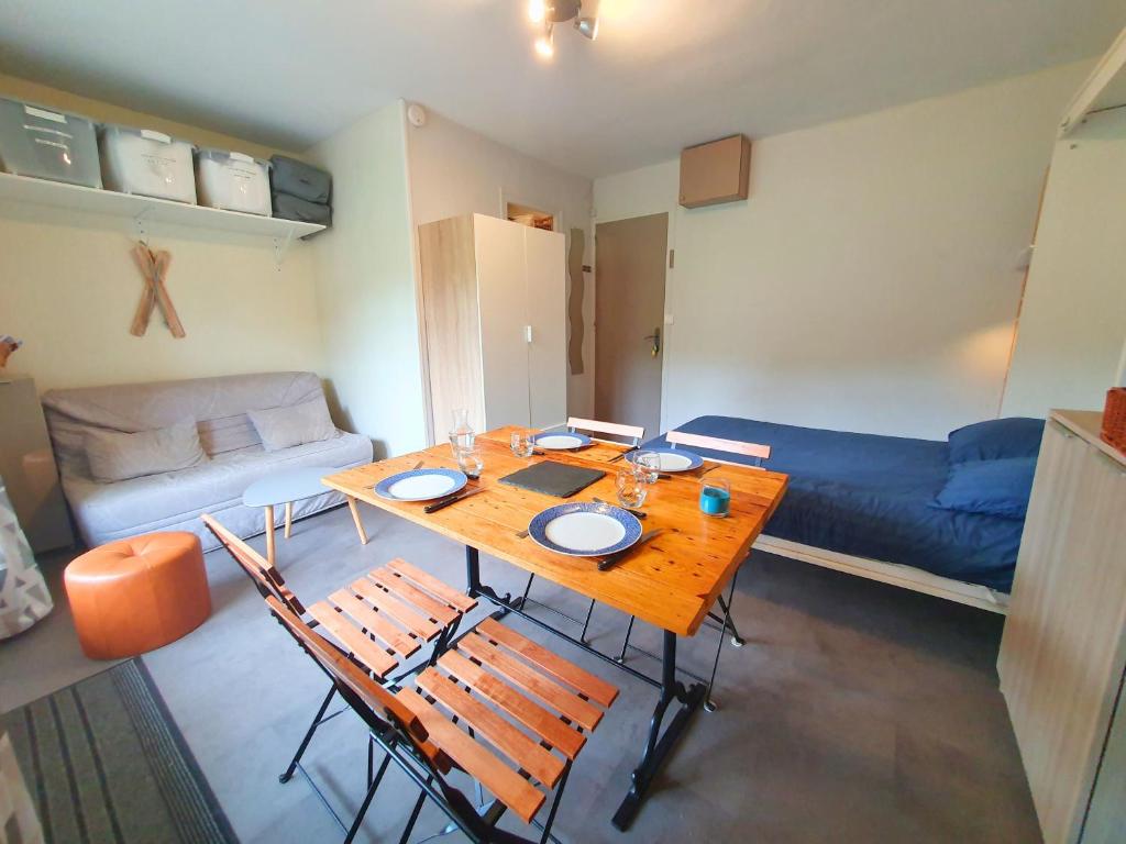 a living room with a table and chairs and a couch at La Pause Bourboulienne Appartement RDC avec balcon in La Bourboule