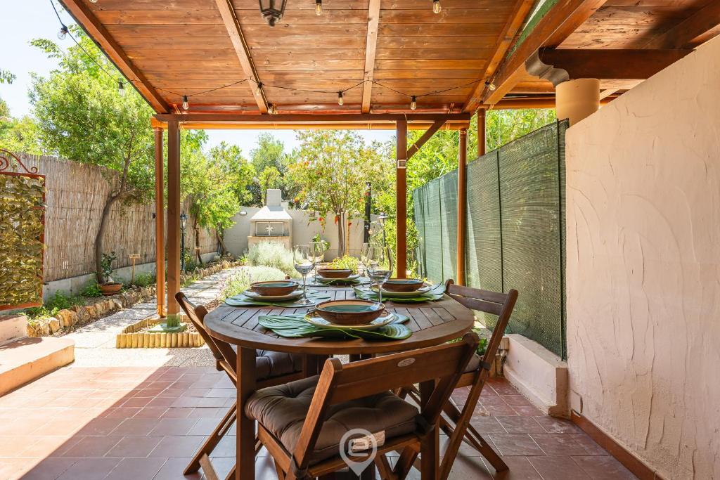 Un patio con una mesa y sillas de madera. en Grace's House, en Villasimius
