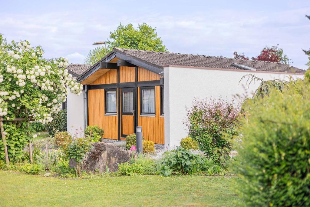 a small house in a yard with a garden at Ferienwohnpark Immenstaad am Bodensee Satteldachhaus Typ 9 SD 65 in Immenstaad am Bodensee