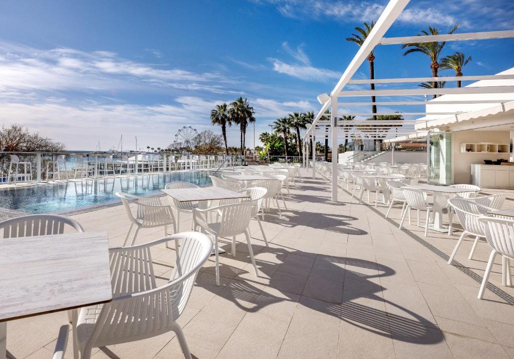 a patio with white tables and chairs next to a pool at Hotel Ocean House Costa del Sol, Affiliated by Meliá in Torremolinos