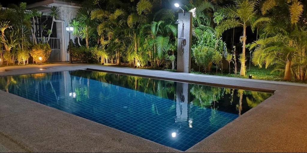 einen Swimmingpool mit Palmen in der Nacht in der Unterkunft Diamond Villas in Ban Phang Phrao