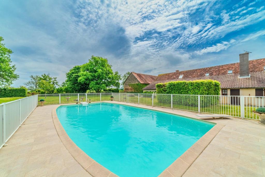 a large swimming pool in a yard with a fence at Le Clos de Villecourt - Piscine Privée in Gueugnon