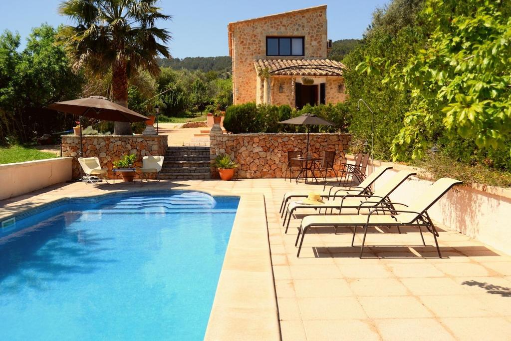 a pool with chairs and a house in the background at Ca'n Nadal Casa rural con piscina in Alaró