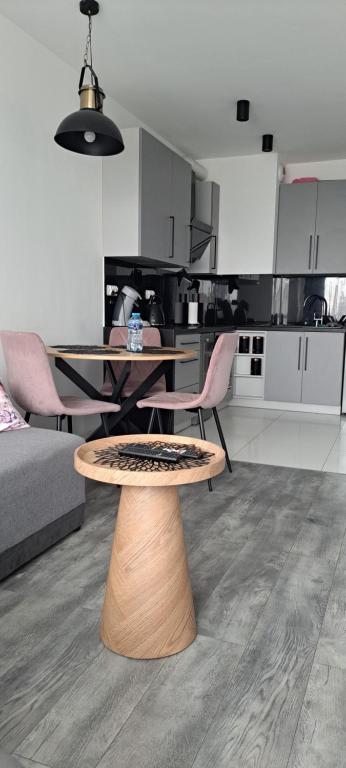 a living room with a table and chairs and a kitchen at Apartament Pudrowy in Koszalin