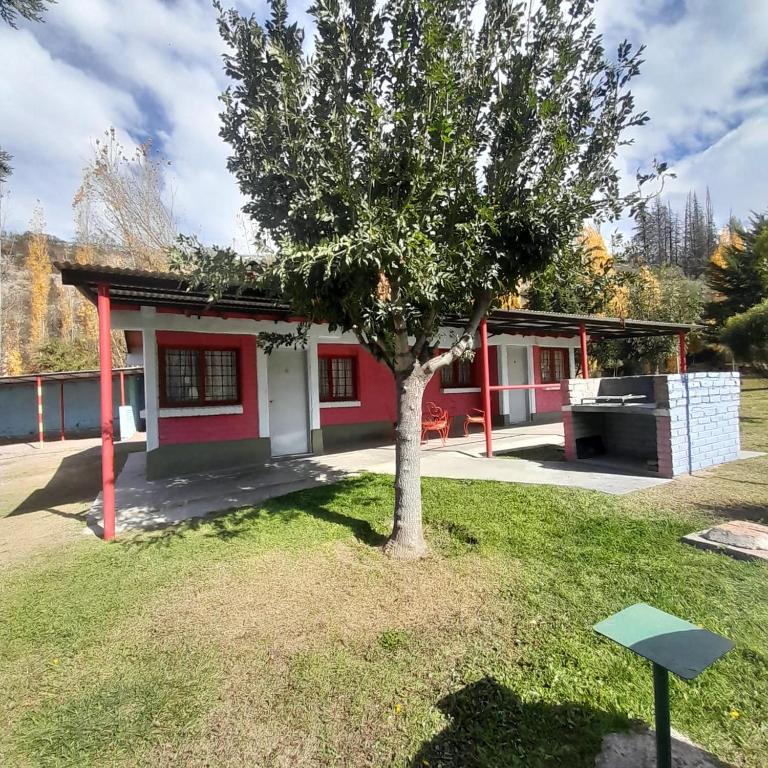 a small red and white house with a tree in a yard at la flor del lugar in Potrerillos