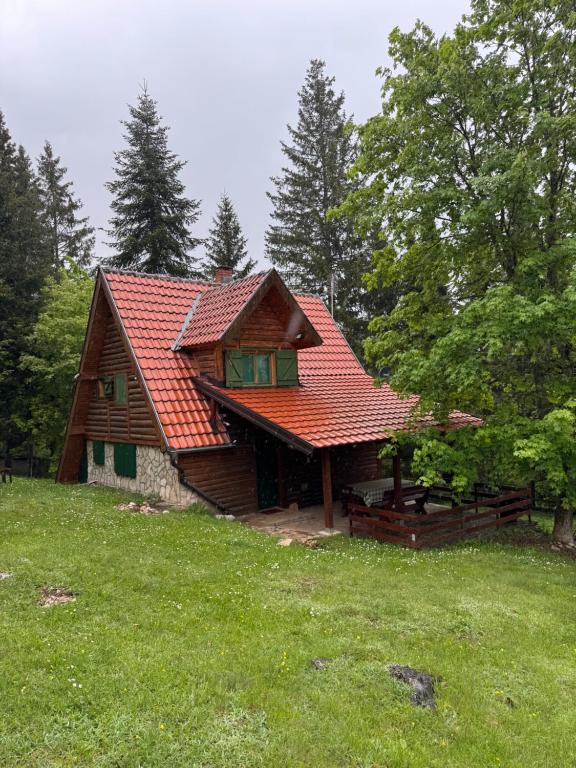 a house with a red roof in a field at Čarobna kućica in Mitrovac