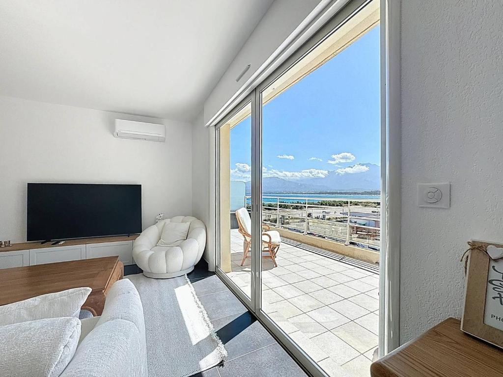 d'un salon avec une télévision et une porte coulissante en verre. dans l'établissement T3 d’Exception avec Vue Panoramique sur la Baie de Calvi, à Calvi