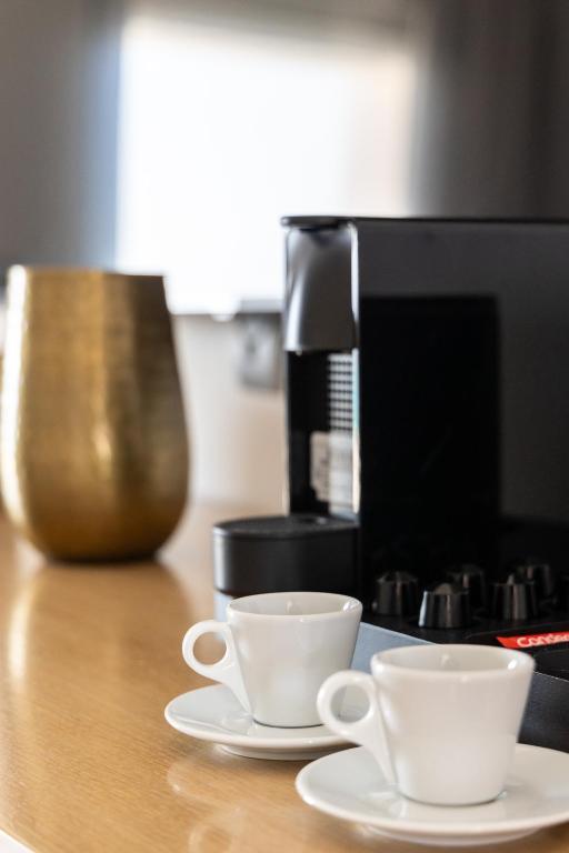 two coffee cups sitting on a counter next to a coffee maker at Golden Milos Beach Ηouse by Domotel in Provatas