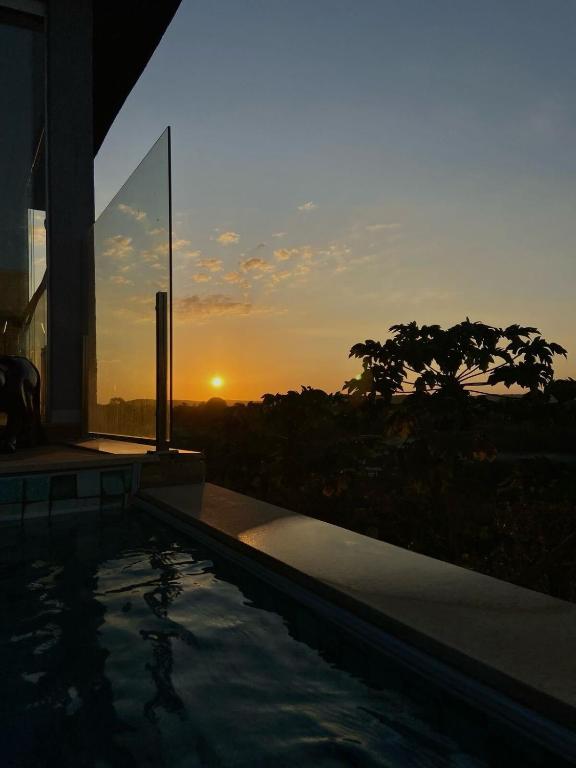 a swimming pool with a sunset in the background at Sítio em Jequitibá Vista Incrível Próximo a Sete Lagoas in Jequitibá