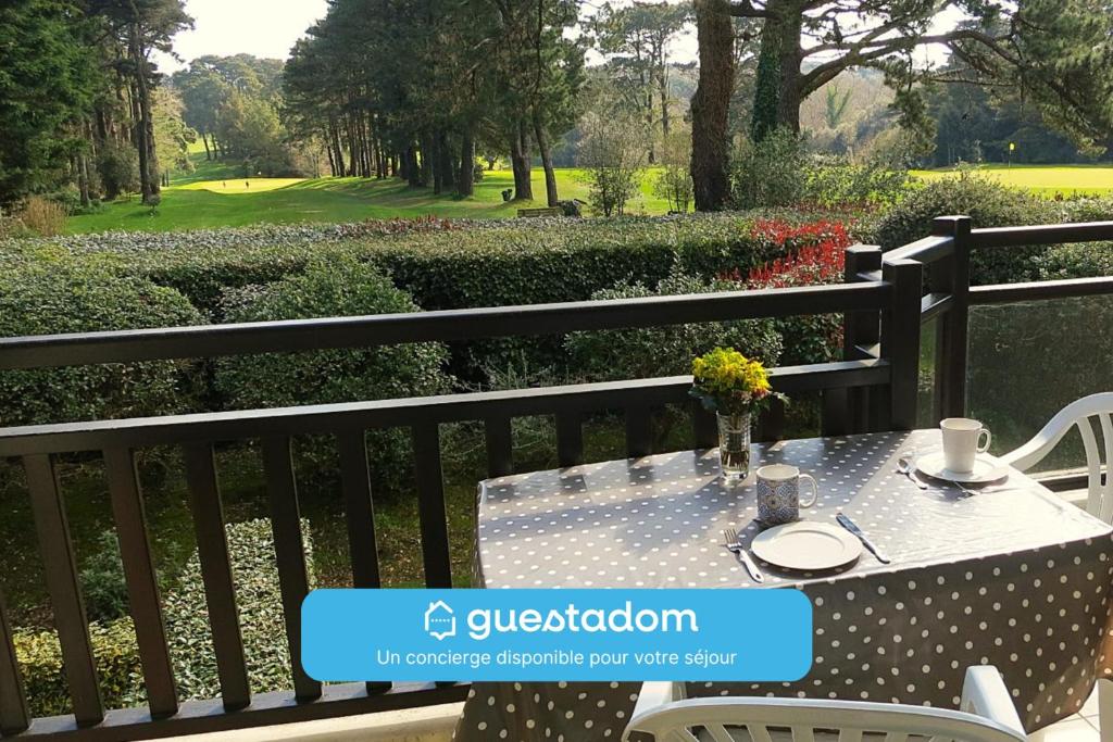 een tafel en stoelen op een balkon met uitzicht op een golfbaan bij T2 cosy - vue sur le golf - proche plage in Pornic