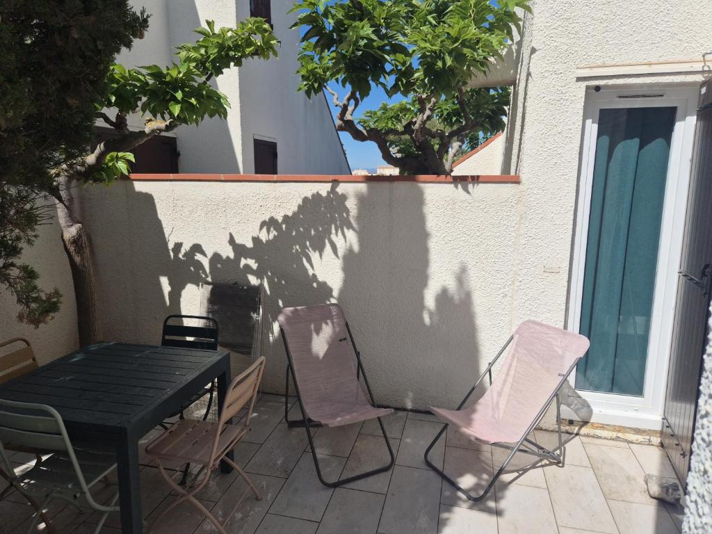un patio avec une table et des chaises sur un patio dans l'établissement Les Marines II - New Design - En bord de mer - Tout Confort - Proche commerces et Animations, au Barcarès