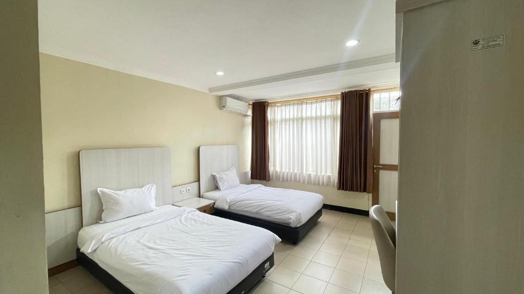 una camera d'albergo con due letti e una finestra di tekMIRA Hotel a Bandung