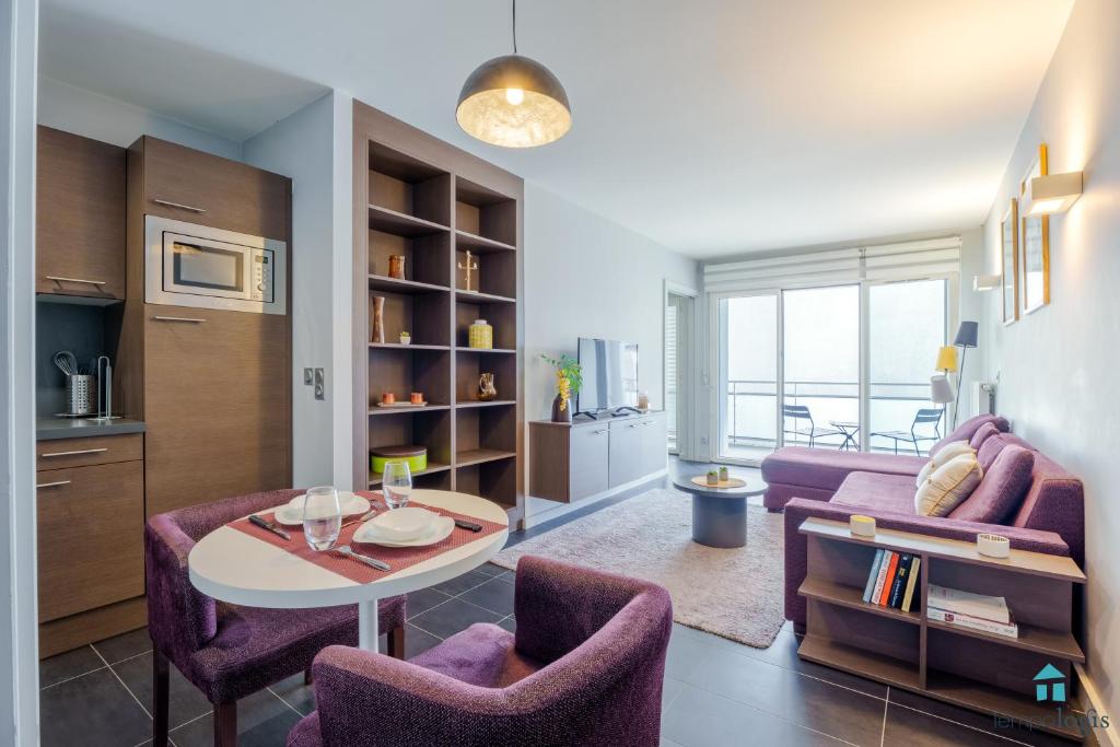 a living room with purple chairs and a table at Apparthôtel Tempologis - St Germain à Grenoble in Grenoble