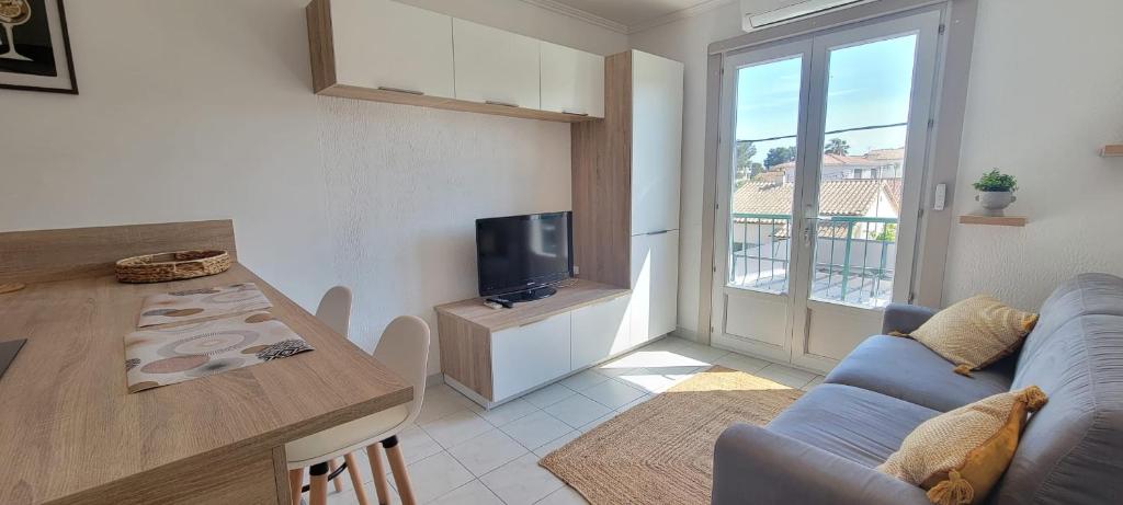 Il comprend un salon doté d'un canapé et une cuisine équipée d'une télévision. dans l'établissement Cozy studio with balcony near beach, à Fréjus