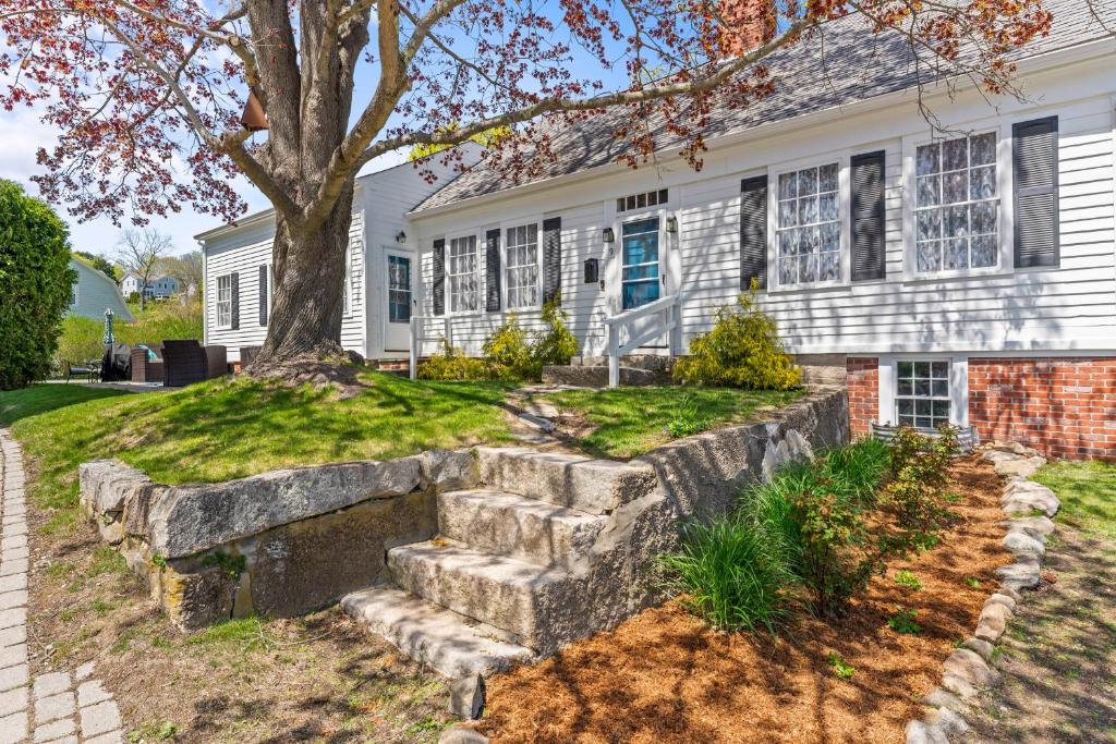a white house with a tree and a stone wall at Historic Waterfront Home and Cottage in Groton