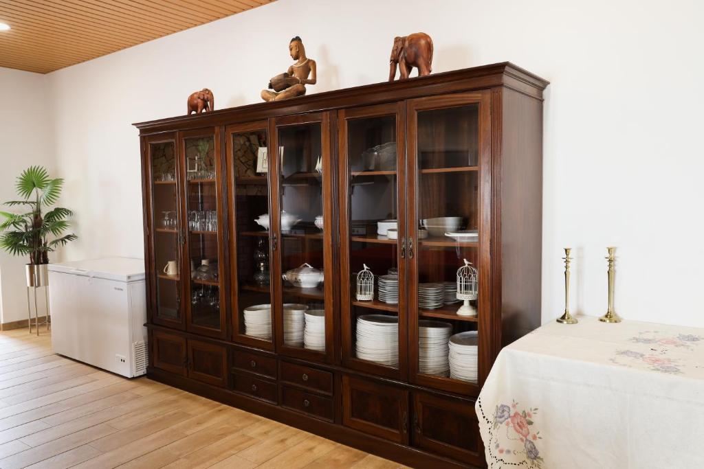 a wooden cabinet with dishes in it in a room at QUINTA das OLIVEIRAS COUNTRY HOUSE in Marinhais