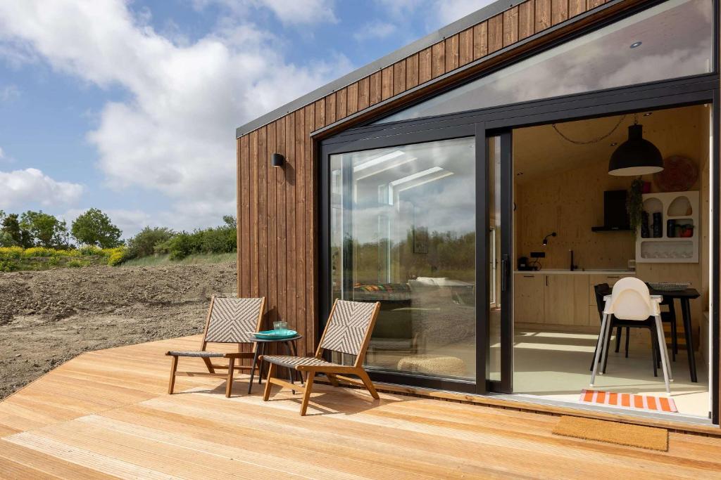 ヴェストカペレにあるHello Zeeland - Tiny House Zeeuwse Liefde 16のガラス戸と椅子付きのデッキ