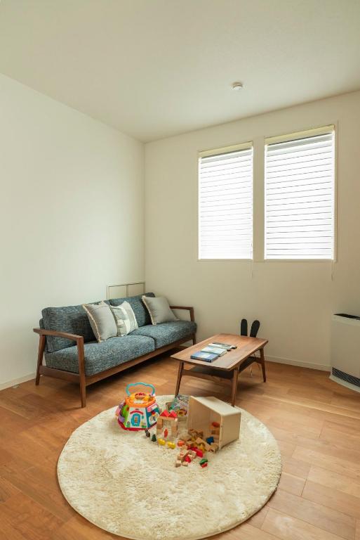 a living room with a couch and a table at Mova Villa Koshi 三澤 2 - 新築一軒家貸切 無料駐車場付 ファミリー向け キッズフレンドリーな宿 in Yuge