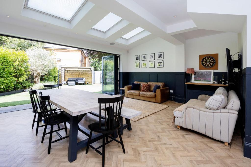 Una sala de estar con una mesa y sillas y un sofá. en Veeve - The Garden Home, en Londres