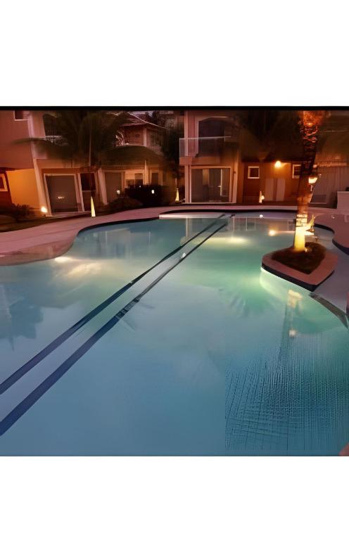 a large swimming pool in a hotel at night at Adorável Casa em Cond. de frente para a Praia Rasa in Búzios