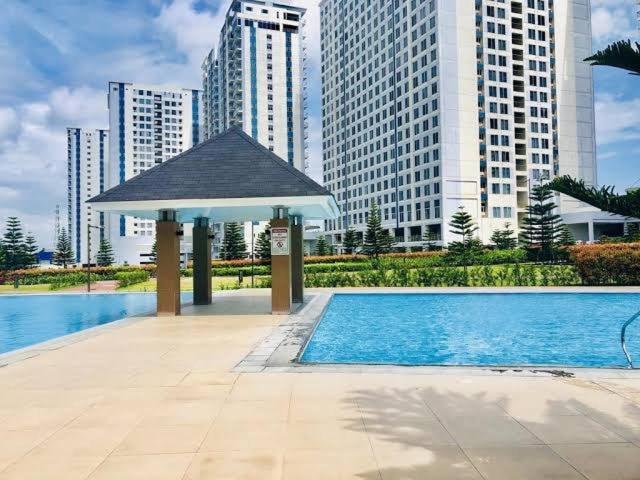 a swimming pool with a gazebo in front of some buildings at Wind Residences Cool suites 1BR unli Wifi, PrimeVideo, Nice pool, Near Malls in Kaybagal