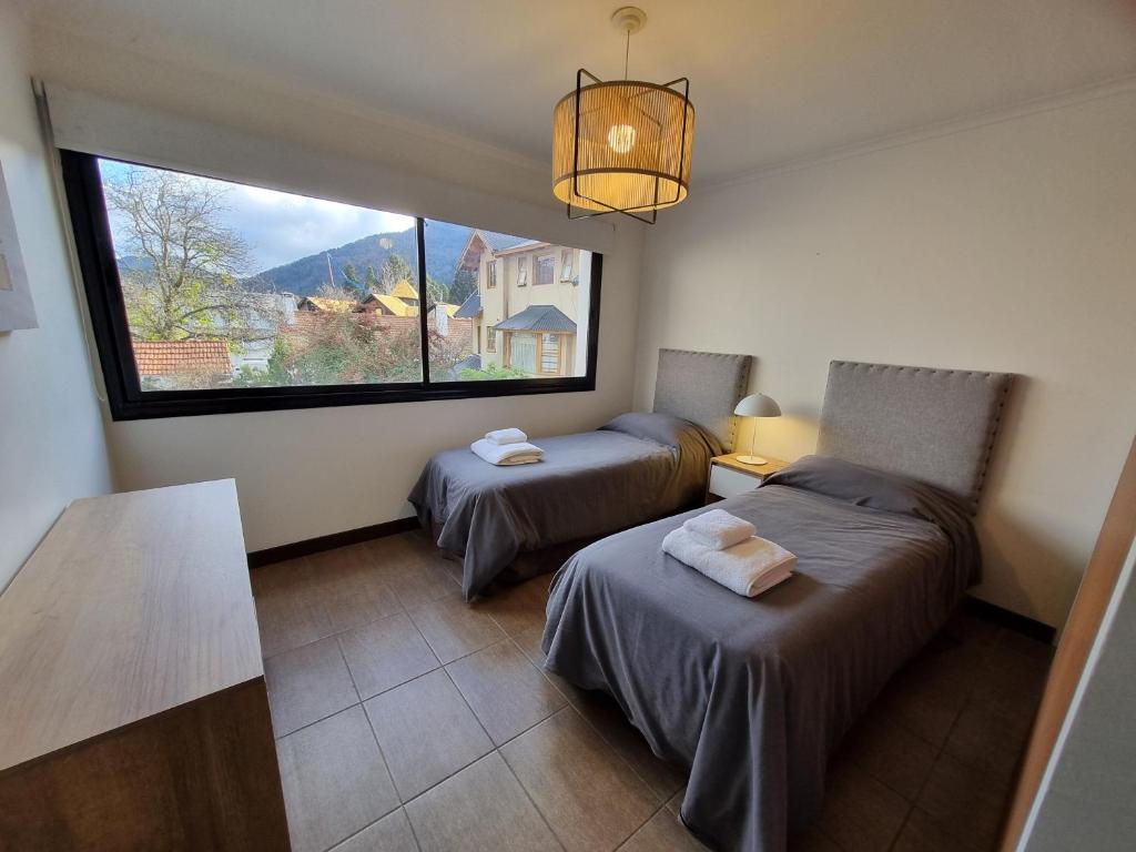 a room with two beds and a large window at Ruka 7- Andarlibre in San Martín de los Andes