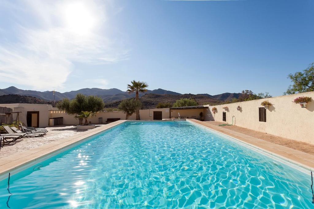 a swimming pool in a resort with mountains in the background at Cortijo El Sotillo in San José
