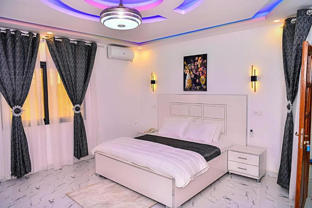 a white bedroom with a white bed and curtains at RELAX RESIDENCES Aéroport AIBD 