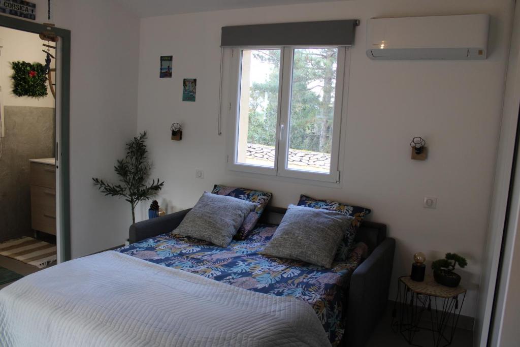una camera da letto con un letto con cuscini e una finestra di Studio Villa Boca a Prunelli-di-Fiumorbo