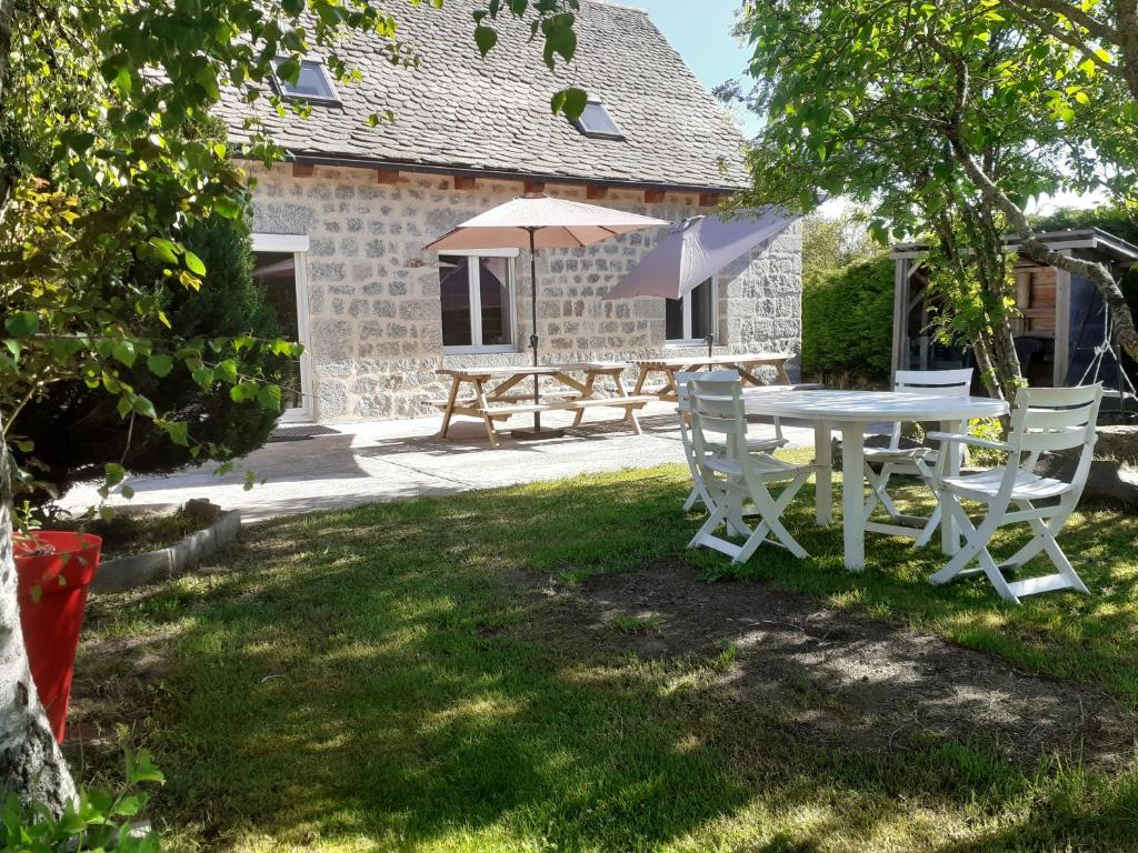 - une table, des chaises et un parasol dans la cour dans l'établissement L'estive gîte 4 étoiles, à Nasbinals