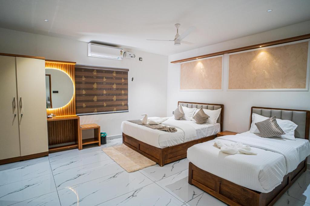 a bedroom with two beds and a mirror at DQ Premium Apartments in Ernakulam