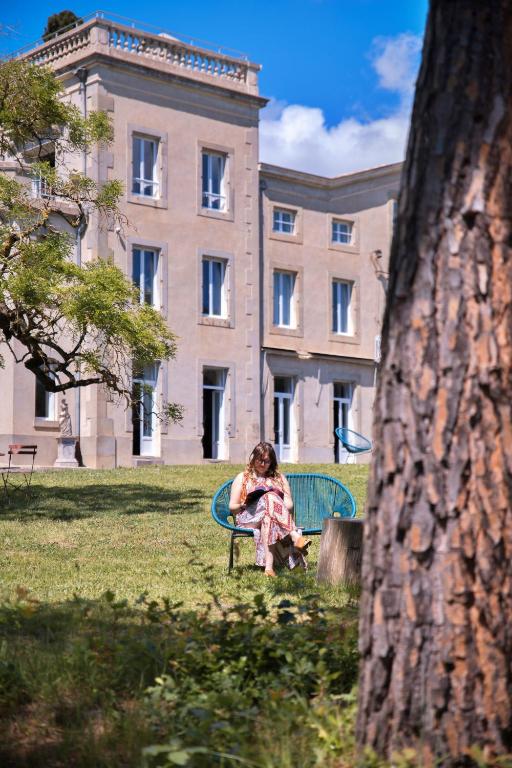 une femme assise sur un banc devant un bâtiment dans l'établissement Le Château de La Seigne, à Villemoustaussou