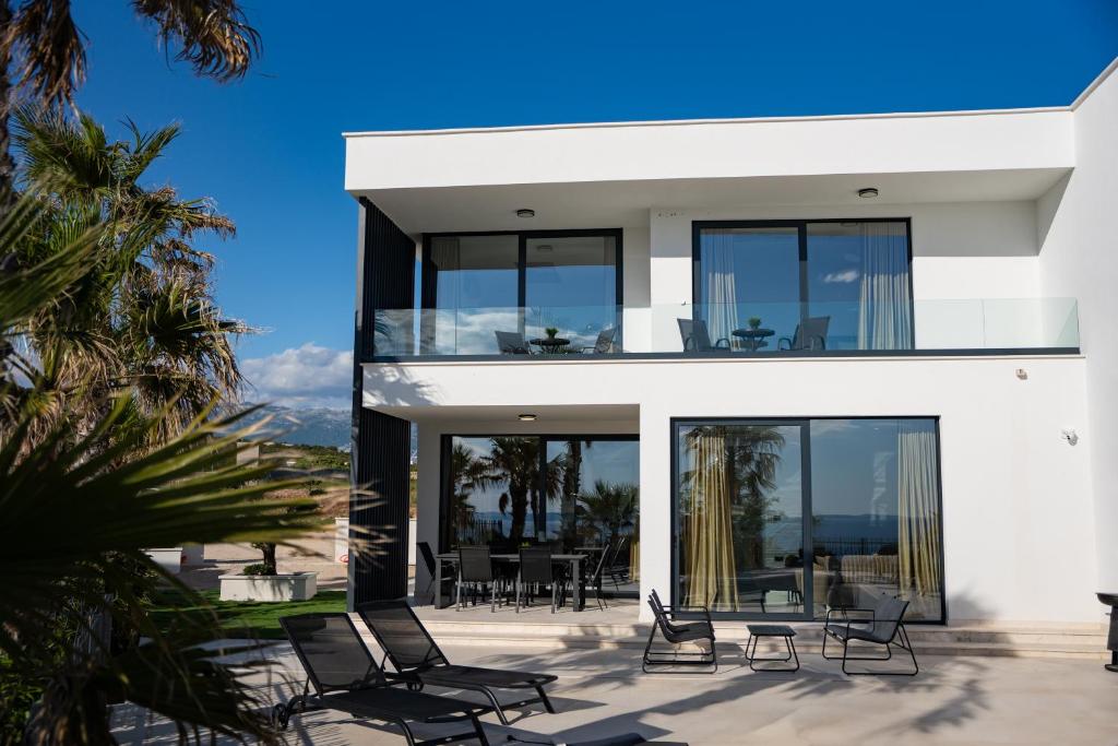 a white house with black windows and chairs on a patio at Villa New York in Novalja