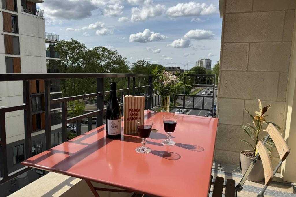 - une table rouge avec deux verres de vin sur le balcon dans l'établissement Lovely 80 m balcony near Paris, à Saint-Ouen
