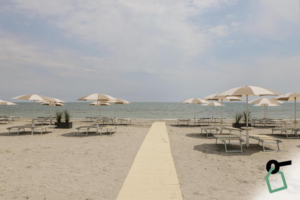 a beach with tables and chairs and umbrellas at Hotiday Milano Marittima Pineta in Milano Marittima