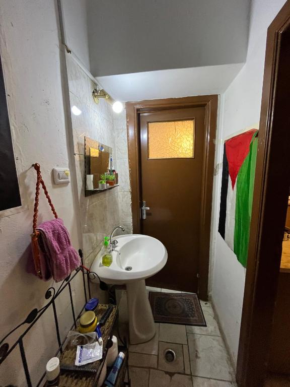 a small bathroom with a sink and a door at bayt alrahaal in Amman