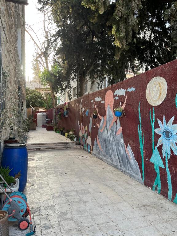 a wall with graffiti on it next to a sidewalk at bayt alrahaal in Amman