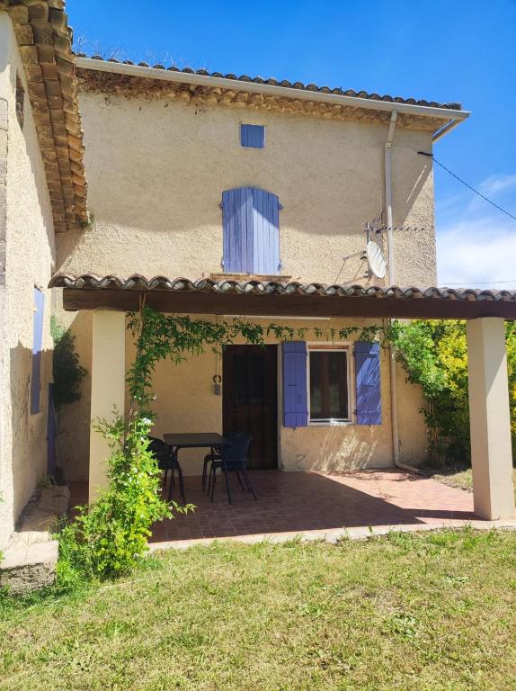 une terrasse avec une table à l'extérieur d'une maison. dans l'établissement Les petits volets bleus, à Bouchet