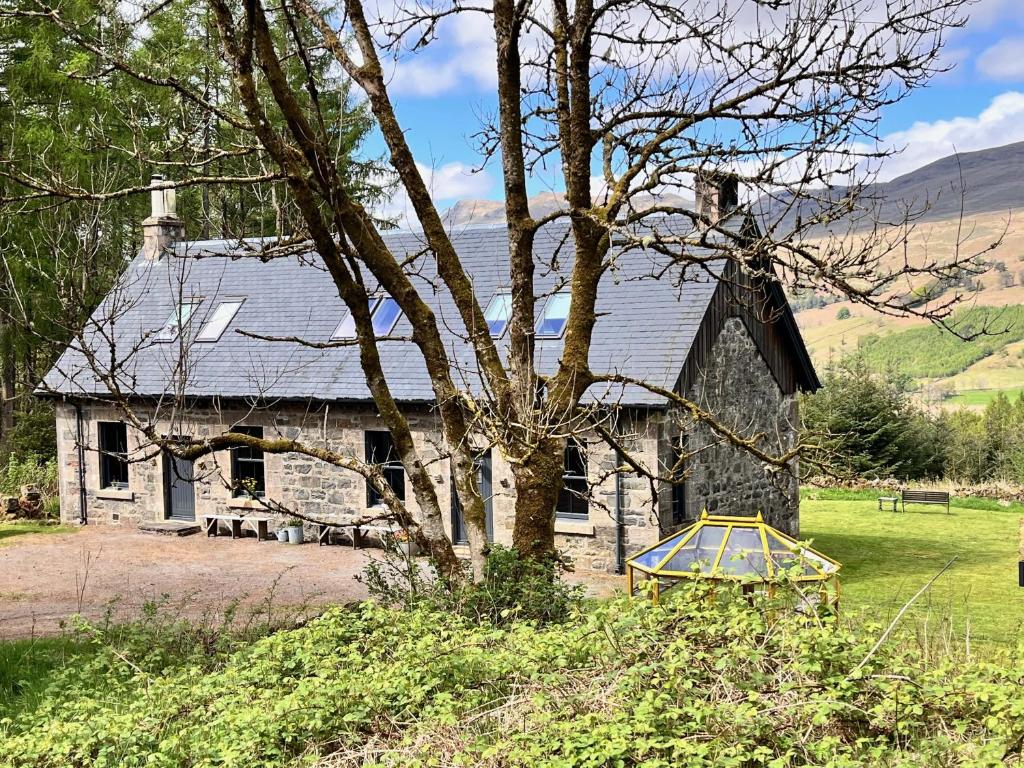 a stone house with a tree in front of it at Railway Cottage in Killin