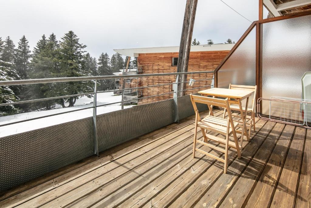 une terrasse en bois avec une table et une chaise sur un balcon dans l'établissement Le Robero - proche dune station de ski, à Chamrousse