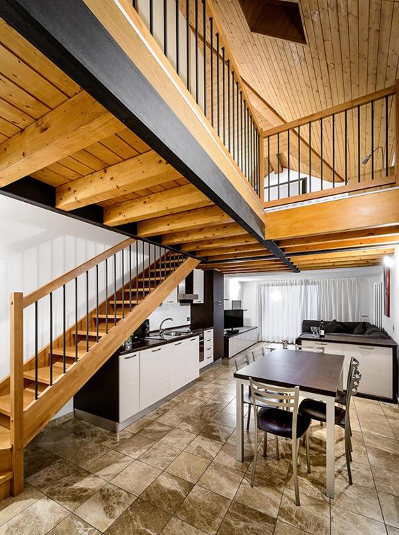 a kitchen with a table and a wooden staircase at Faber Apartments-Residence Style in Arona