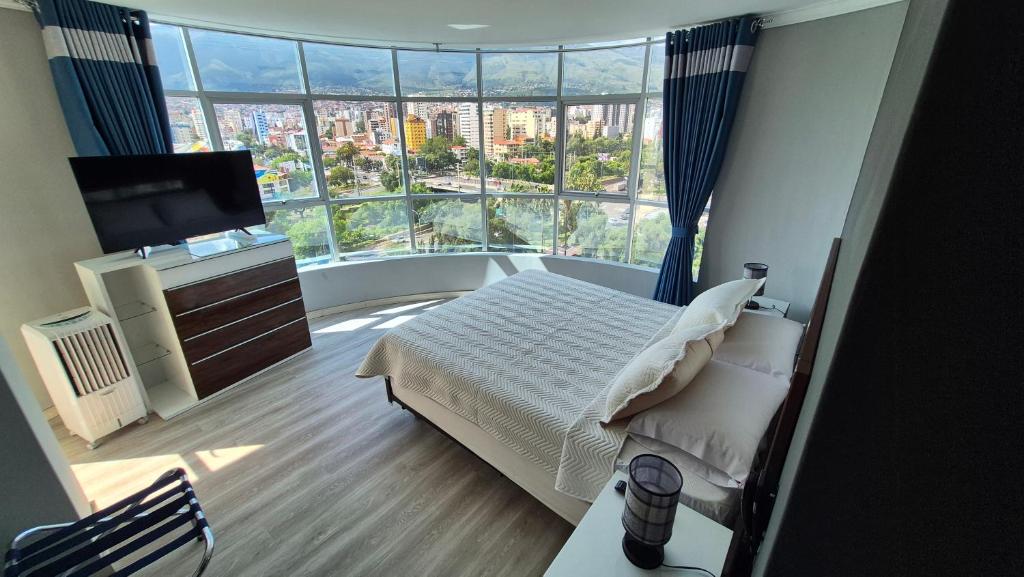 a bedroom with a bed and a large window at Premium Apartamentos Torre Azul in Cochabamba