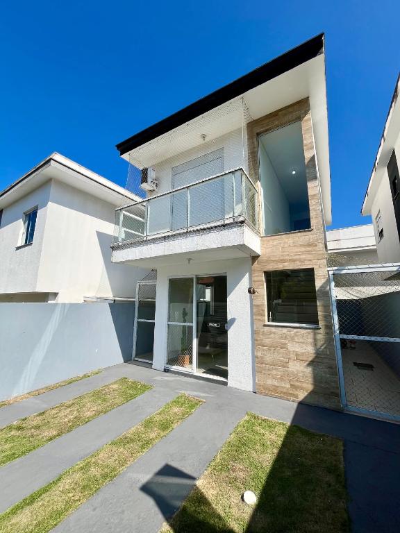 ein weißes Haus mit Balkon und Garten in der Unterkunft Casa prox. a praia do Campeche in Florianópolis