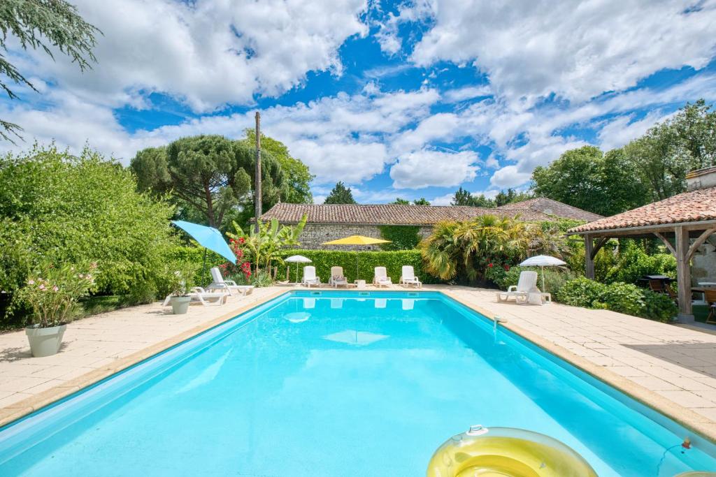 ein Pool mit Stühlen und Sonnenschirmen neben einem Haus in der Unterkunft Maison de Campagne à Cunèges in Cunèges